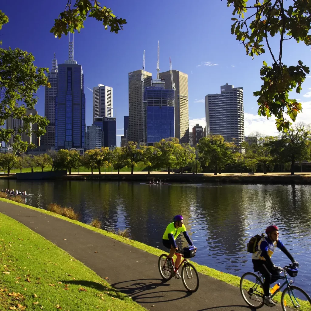 Cyclists by the river with a city skyline
