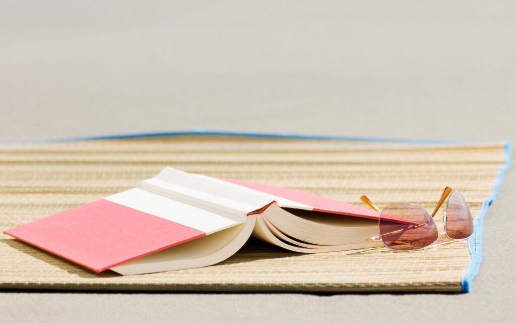 Open book and sunglasses resting on a beach